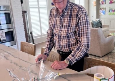 Smiling older man stands at kitchen counter.