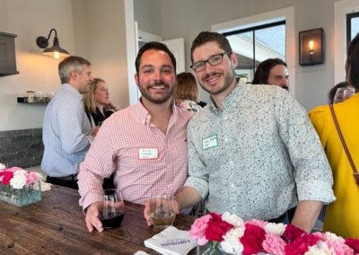 Two men smiling holding wine glasses.